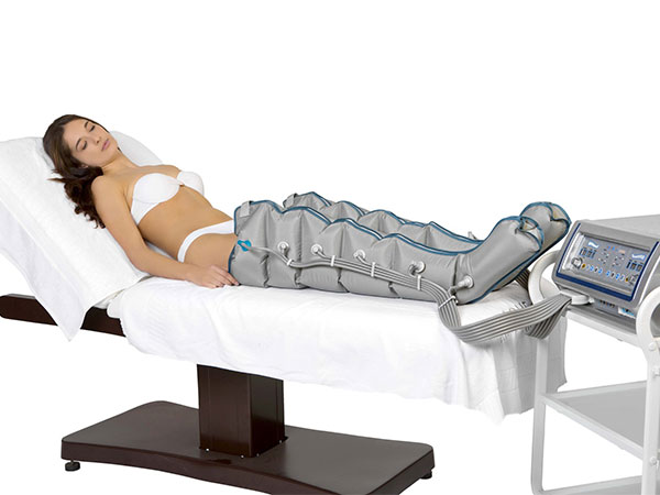 Femme couchée sur une table à massage recevant un soin de pressothérapie
